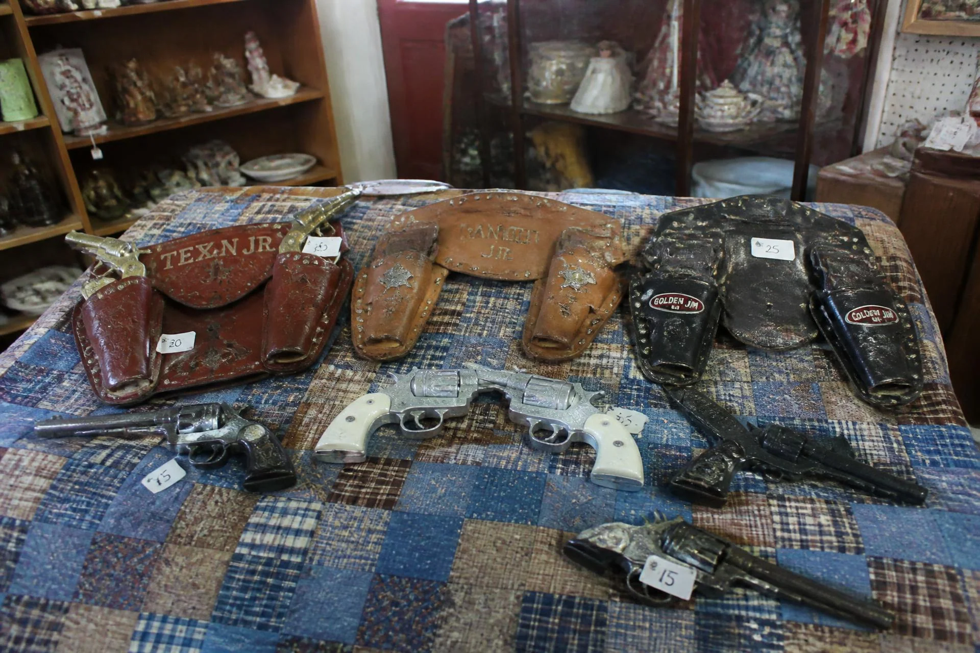 Vintage cap guns and leather holsters displayed at an antique mall booth